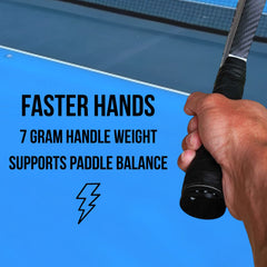 A close-up of a hand gripping a tennis paddle handle with promotional text on a blue table tennis court background. The text reads: 'FASTER HANDS 7 GRAM HANDLE WEIGHT SUPPORTS PADDLE BALANCE' with a lightning icon.